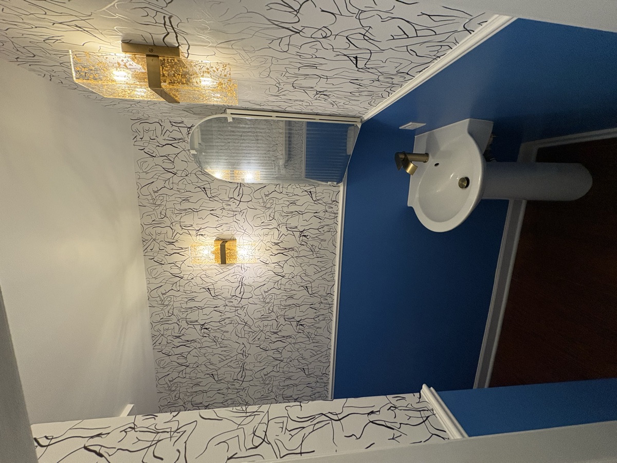 Bathroom after renovation - wallpaper, blue accent wall, gold fixtures, mirror and vanity